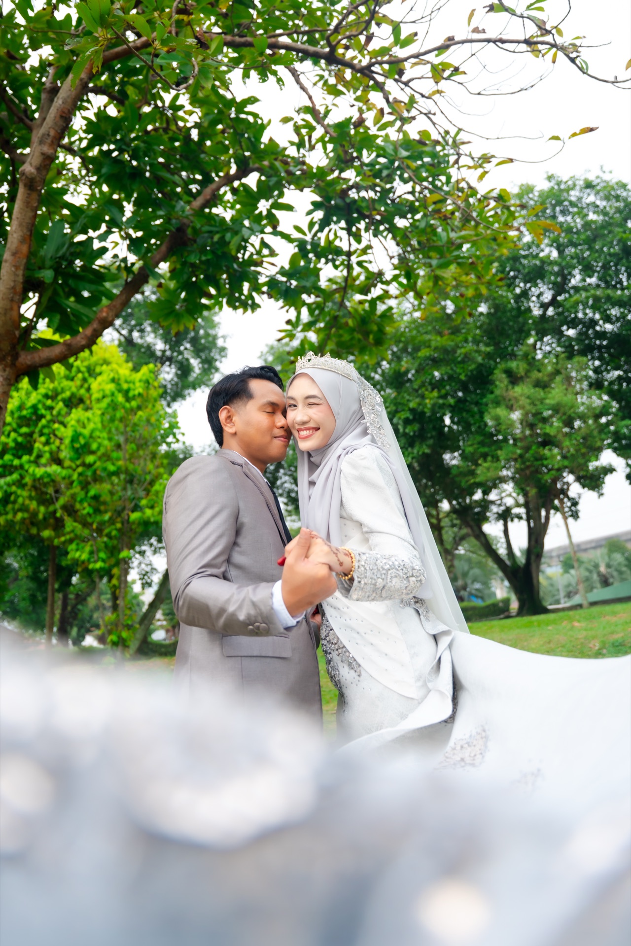 A smiling wedding couple surrounded by a lush garden